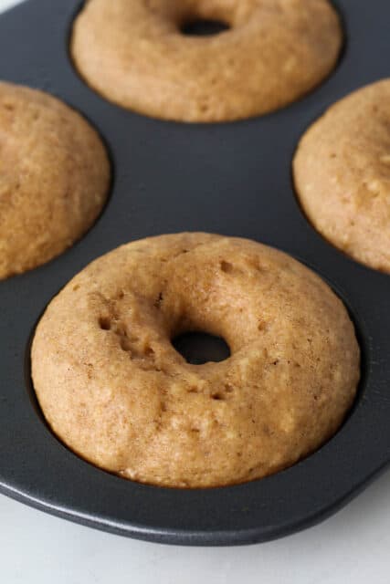 Baked apple cider donuts in a donut pan.