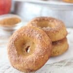 A cider donuts covered in cinnamon sugar, leaving up again a stack of donut