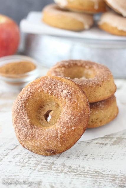 A cider donuts covered in cinnamon sugar, leaving up again a stack of donut