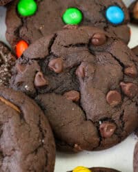 Close up view of assorted chocolate cake mix cookies filled with Reese's Minis, chocolate chips, M&Ms, and others covered with sanding sugar.