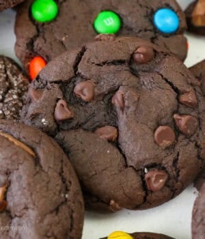 Close up view of assorted chocolate cake mix cookies filled with Reese's Minis, chocolate chips, M&Ms, and others covered with sanding sugar.