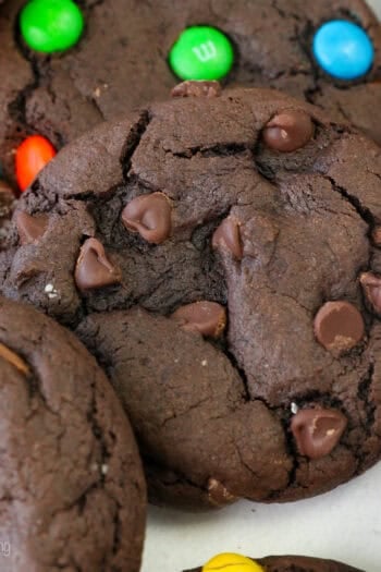 Close up view of assorted chocolate cake mix cookies filled with Reese's Minis, chocolate chips, M&Ms, and others covered with sanding sugar.