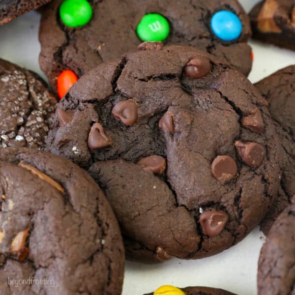 Close up view of assorted chocolate cake mix cookies filled with Reese's Minis, chocolate chips, M&Ms, and others covered with sanding sugar.