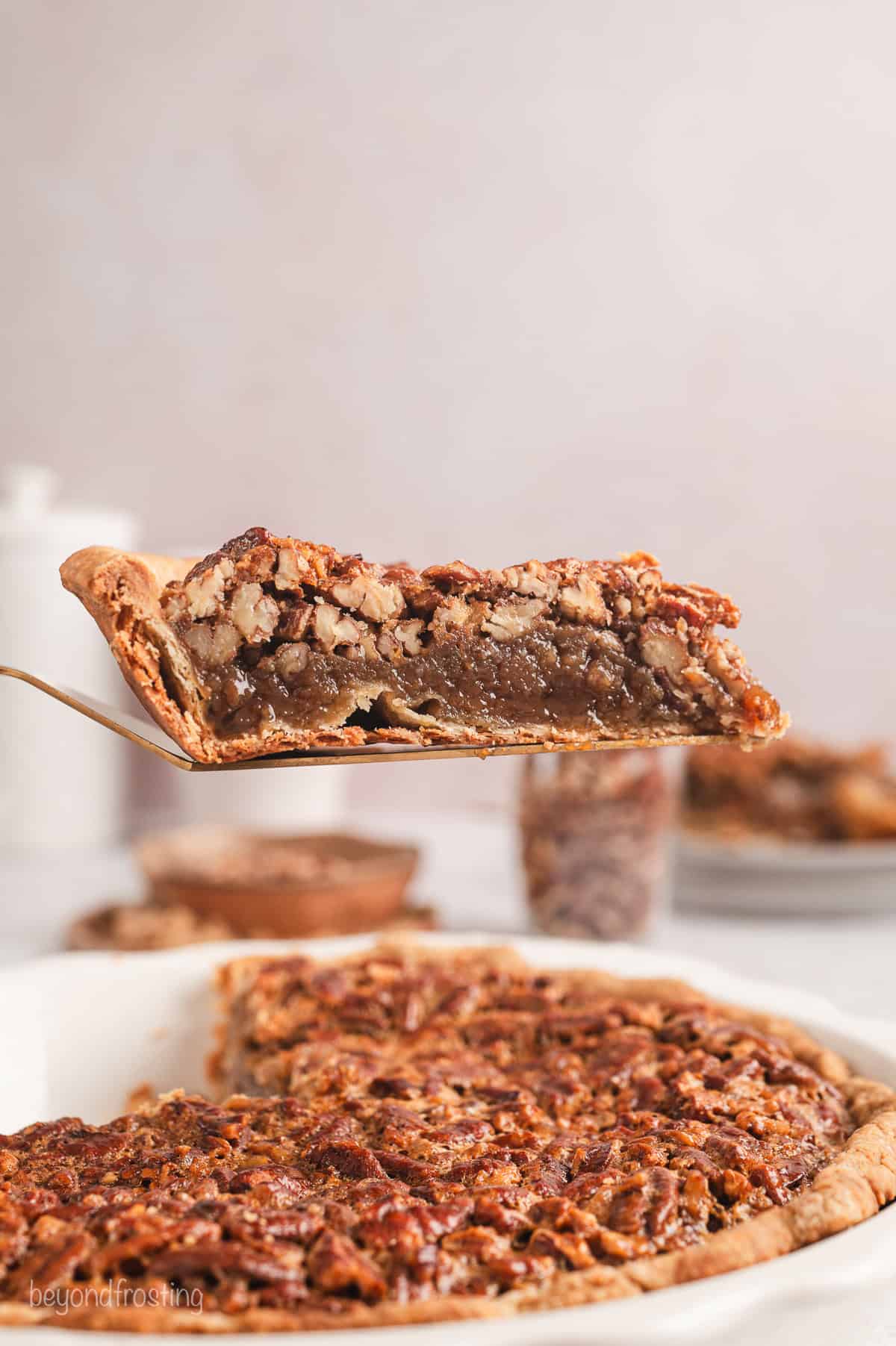 A slice of pecan pie lifted above the rest of the pie in a pie plate.