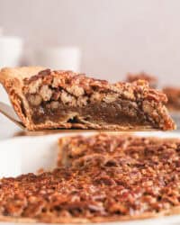 A slice of pecan pie lifted above the rest of the pie in a pie plate.