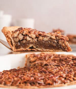 A slice of pecan pie lifted above the rest of the pie in a pie plate.