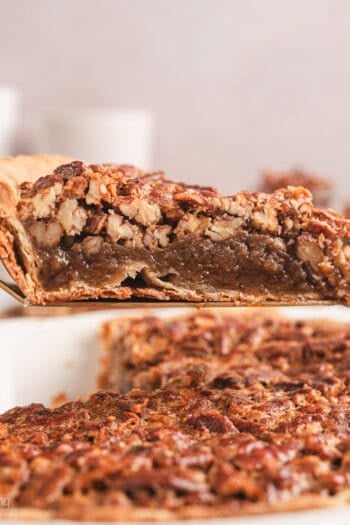 A slice of pecan pie lifted above the rest of the pie in a pie plate.