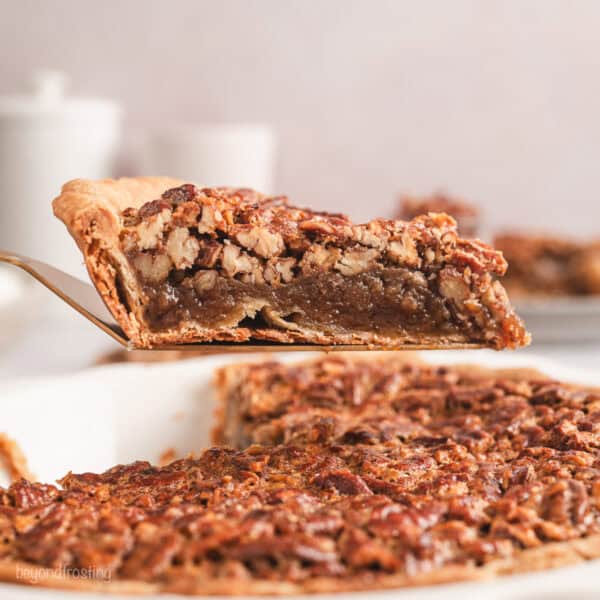 A slice of pecan pie lifted above the rest of the pie in a pie plate.