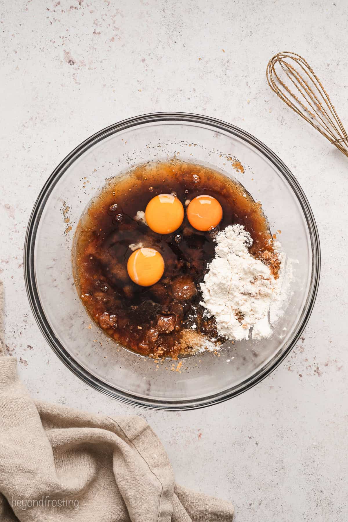 Eggs and dry ingredients added to filling ingredients in a glass bowl.