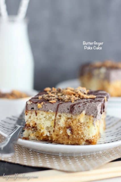 This Butterfinger Poke Cake is a vanilla cake baked with Butterfinger pieces, soaked in a butterscotch pudding and covered with chocolate whipped cream.