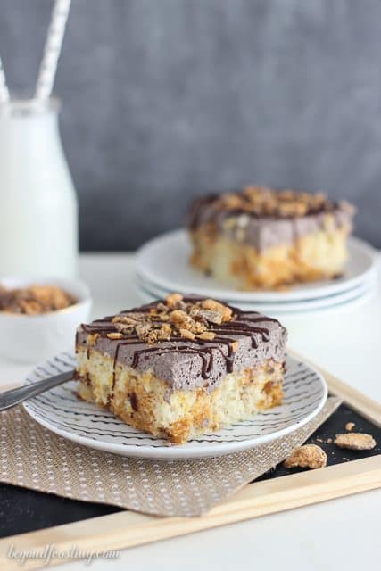 This Butterfinger Poke Cake is a vanilla cake baked with Butterfinger pieces, soaked in a butterscotch pudding and covered with chocolate whipped cream.