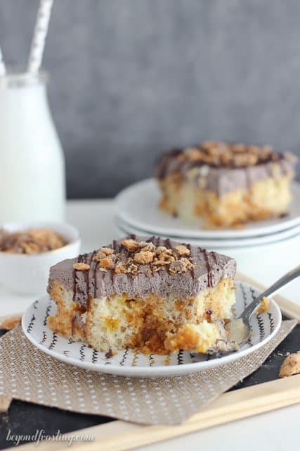 Dig into this Butterfinger Poke Cake! The vanilla cake is filled with Butterfingers bite, butterscotch pudding and topped with chocolate whipped cream!