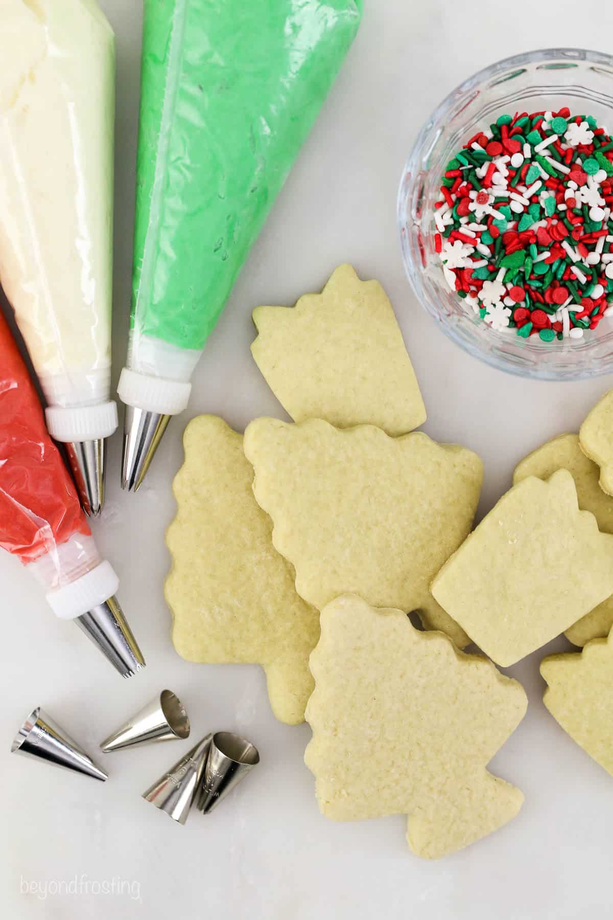 Piping bags of frosting, cut out sugar cookies, and sprinkles