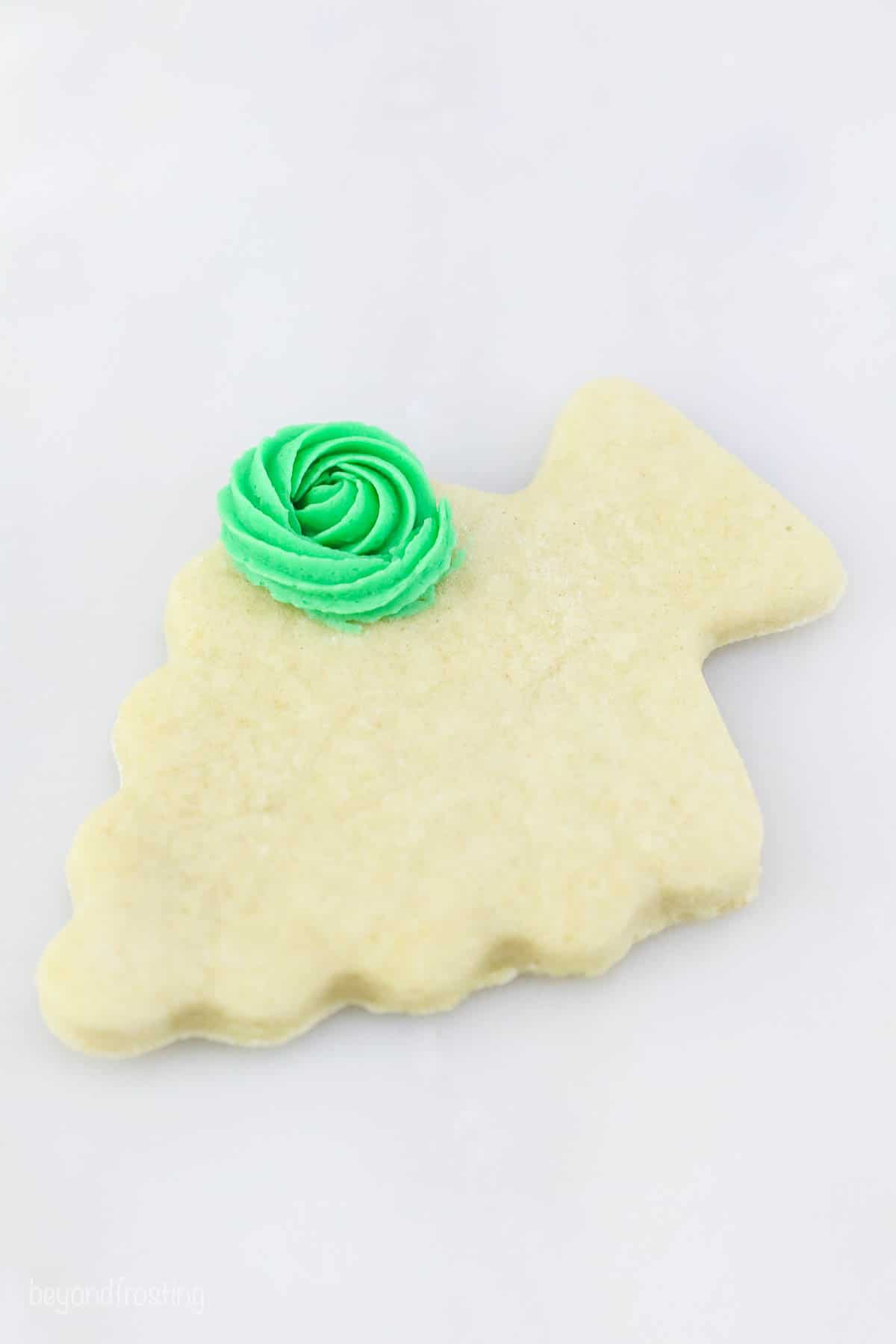 A green frosting rosette on a Christmas tree sugar cookie