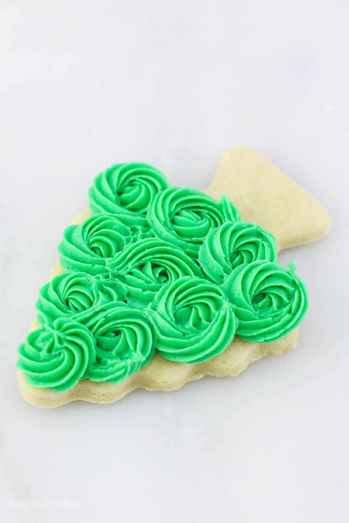 A frosted sugar cookie in the shape of a christmas tree