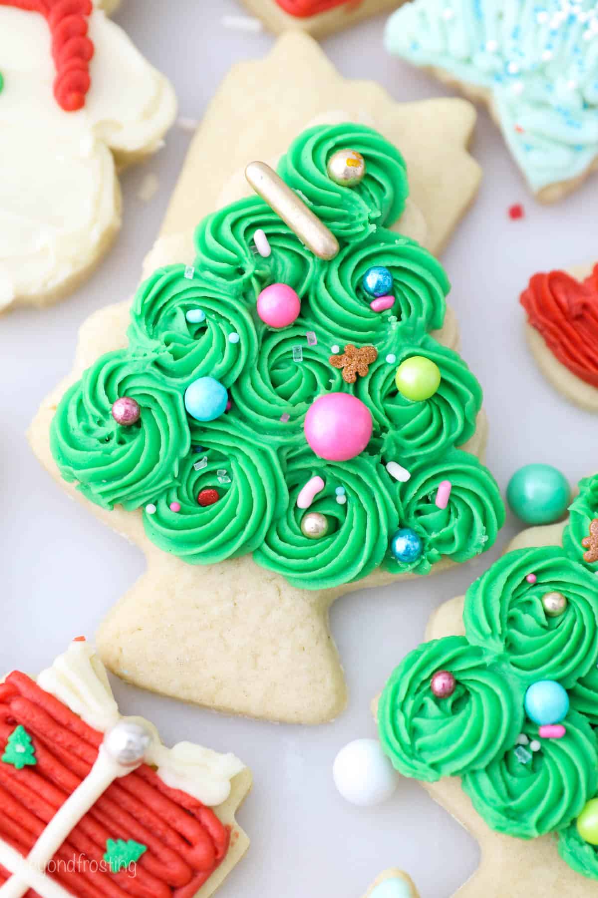 A sugar cookie with buttercream frosting shaped like a christmas tree