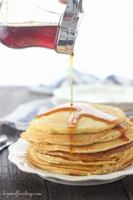 A stack of Dairy-Free Eggnog Pancakes and drizzled with maple syrup.