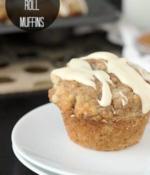 A Cinnamon Roll Muffin drizzled with a vanilla glaze resting atop a white plate.