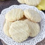 A platter of many perfect lemon cake mix cookies drizzled with white chocolate.