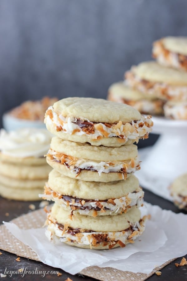 These Samoa Cookie Sandwiches are completely irresistible. The caramel buttercream is sandwiched between two chewy sugar cookies coated with chocolate sauce and rolled in toasted coconut.