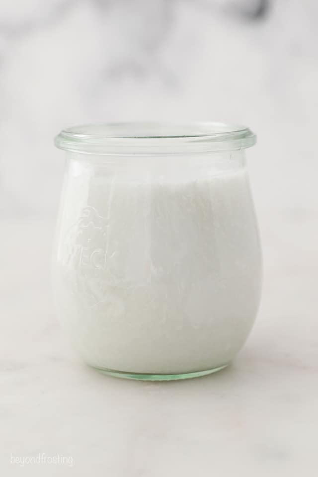 a glass jar with stirred coconut milk