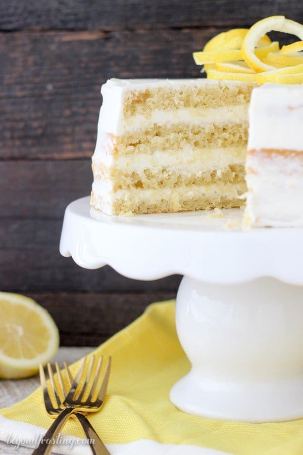 A Lemon Olive Oil Cake with a slice missing on top of a cake stand