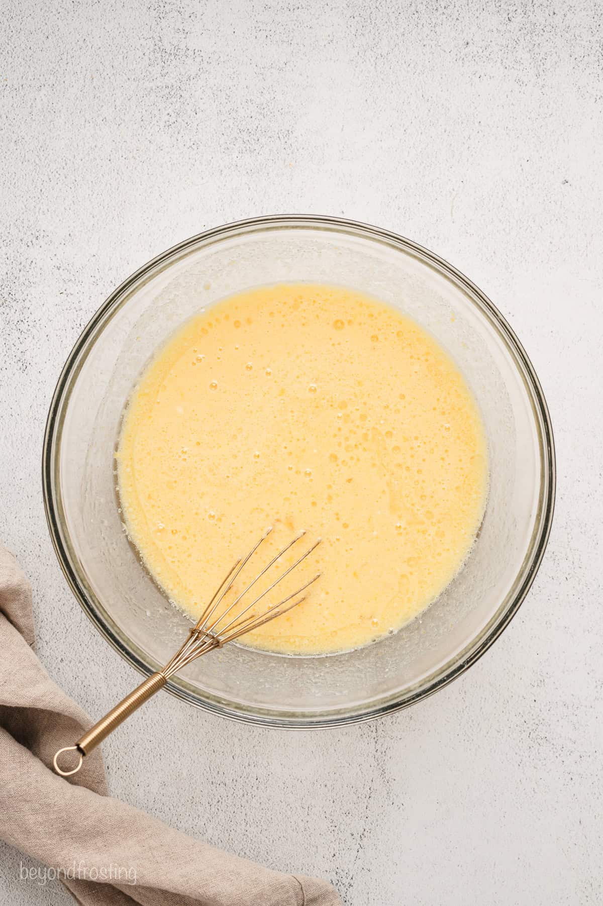 Lemon cake batter in a glass bowl with a whisk.