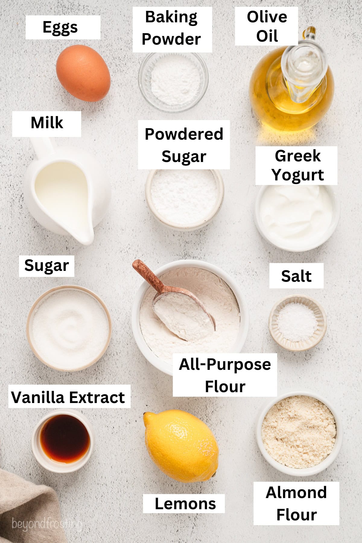 Lemon olive oil cake ingredients with text labels overlaying each ingredient.