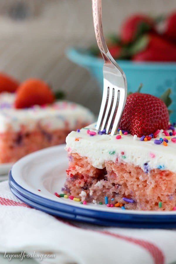 Fork taking a piece of strawberry cake off a slice