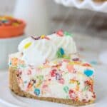 A Piece of No-Bake Fruity Pebbles Cheesecake on a White Plate