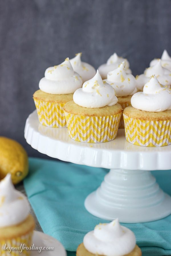 A ruffled white cake stand with cupcakes on top with yellow chevon cupcake liners