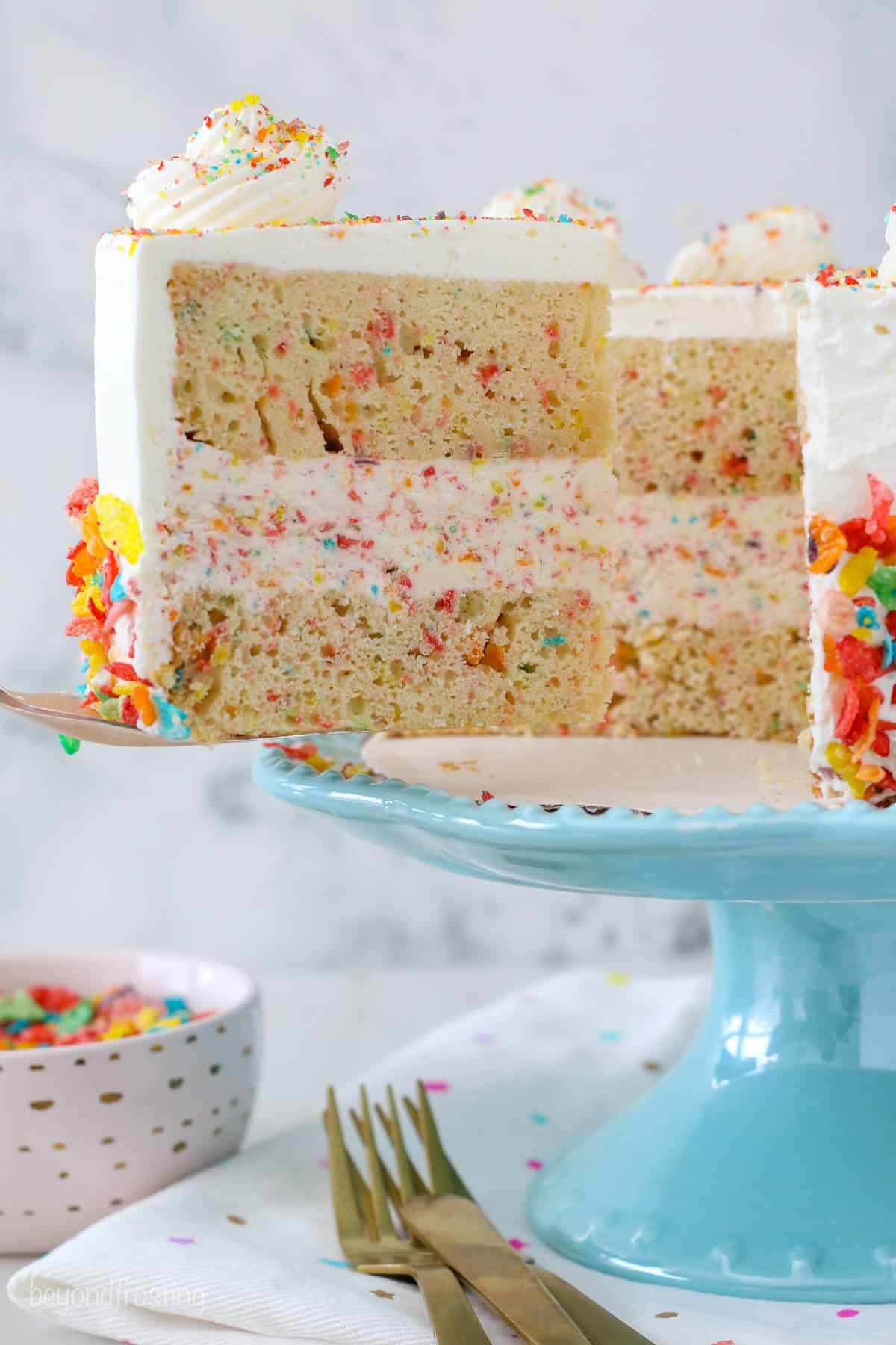 Fruity pebble ice cream cake on a cake stand with a slice missing