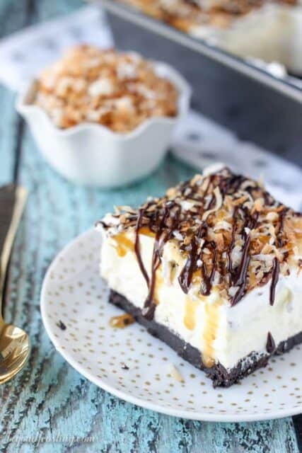 This No-Bake Samoa lush is an icebox cake featuring an Oreo cookie crust, a layer of caramel cheesecake, coconut mousse and a whipped cream topped with caramel, hot fudge and toasted coconut