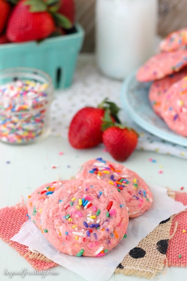 Three pink strawberry cookies on parchment paper.