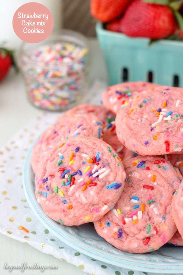 A plate filled with pink cookies with sprinkles.