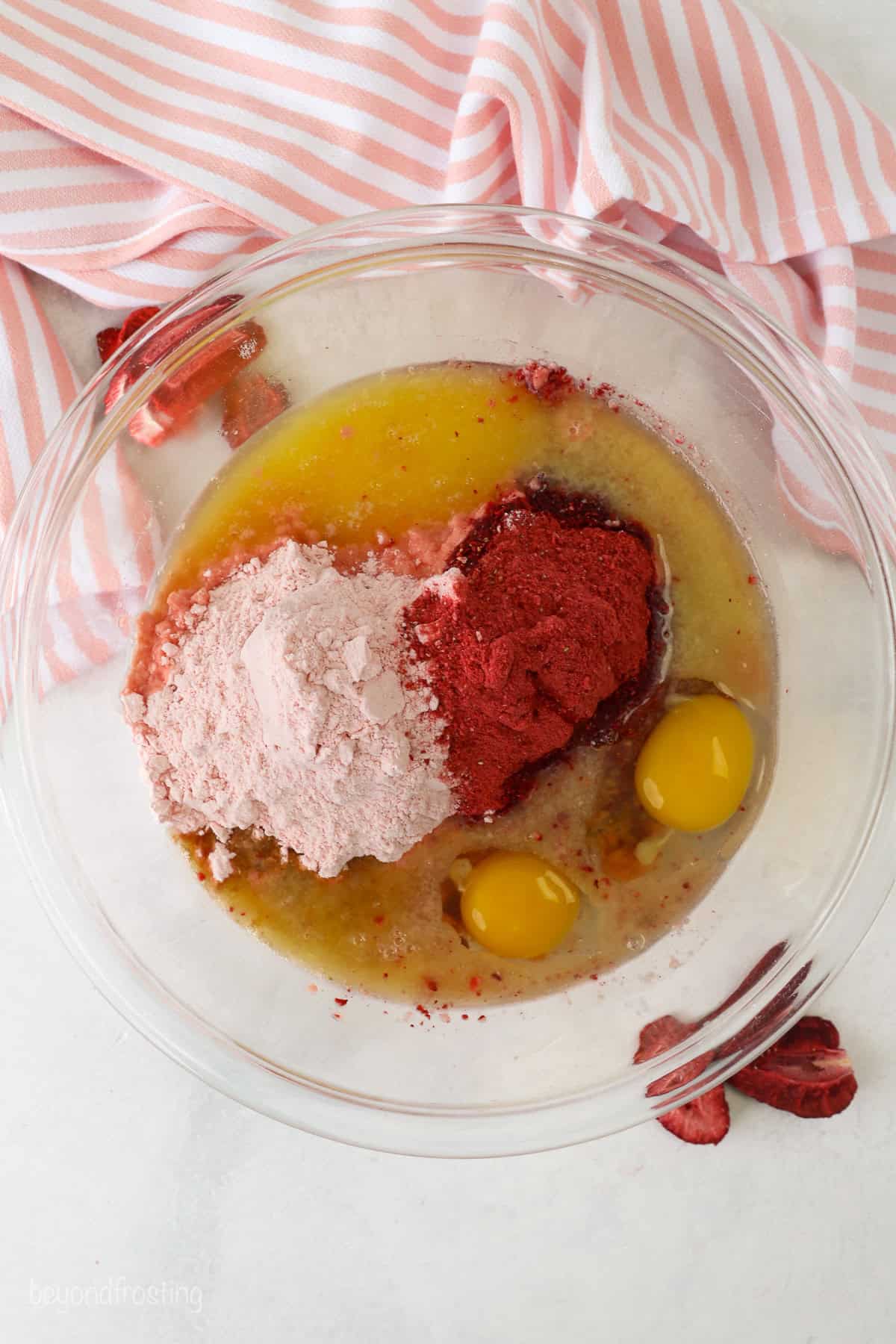 Overhead view of strawberry cake mix cookie ingredients combined in a glass mixing bowl.