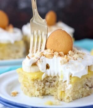 A slice of Easy Banana Pudding Poke Cake topped with Cool Whip and Nilla Wafers