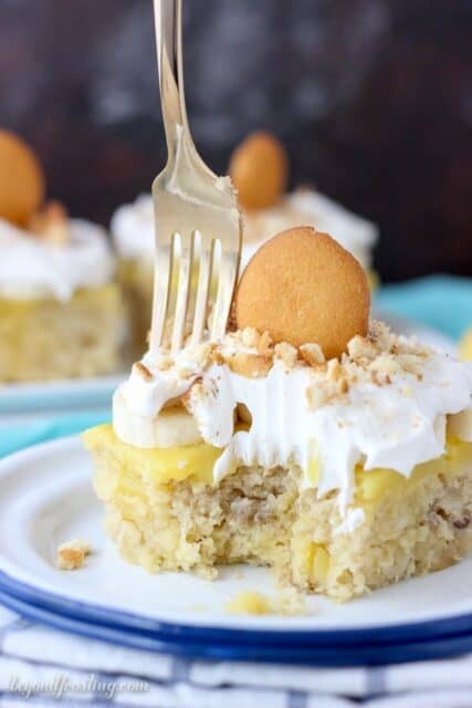 A slice of Easy Banana Pudding Poke Cake topped with Cool Whip and Nilla Wafers