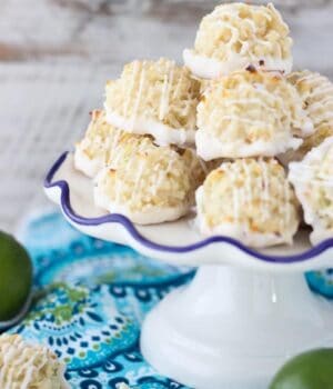 Quick and easy white chocolate coated Coconut Lime Macaroons stacked on a serving platter. Just 7 simple ingredients, these come together in less than 10 minutes. The fresh lime zest is the perfect compliment to this recipe. This is from the cookbook, Out Of The Box Desserts. It is a must-have!