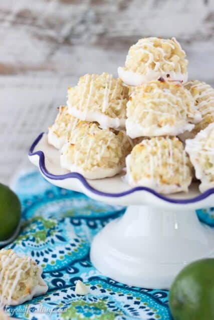 Quick and easy white chocolate coated Coconut Lime Macaroons stacked on a serving platter. Just 7 simple ingredients, these come together in less than 10 minutes. The fresh lime zest is the perfect compliment to this recipe. This is from the cookbook, Out Of The Box Desserts. It is a must-have!