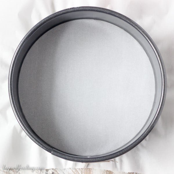 An overhead shot of a springform pan lined with parchment paper.