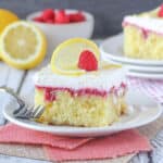 A horizontal shot of alice of lemon cake with raspberry filling and a fruit garnish