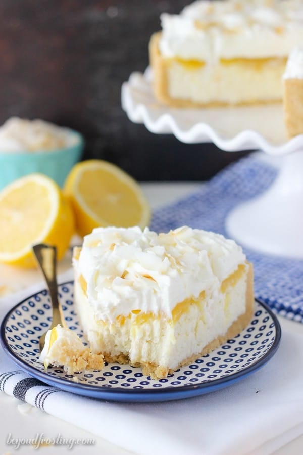 A slice of coconut lemon cheesecake with a bite take out of it on a blue plate