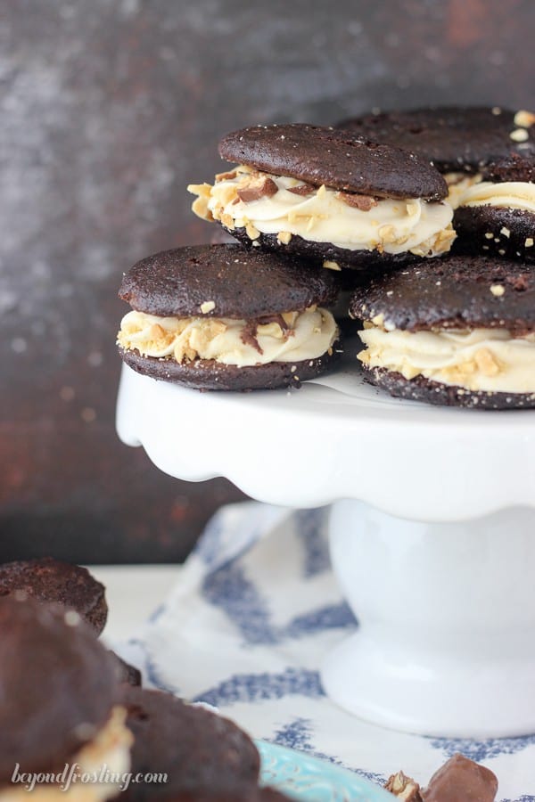 Snicker Whoopie Pies are a delicate chocolate cake with caramel buttercream, salty peanuts and snickers bars.