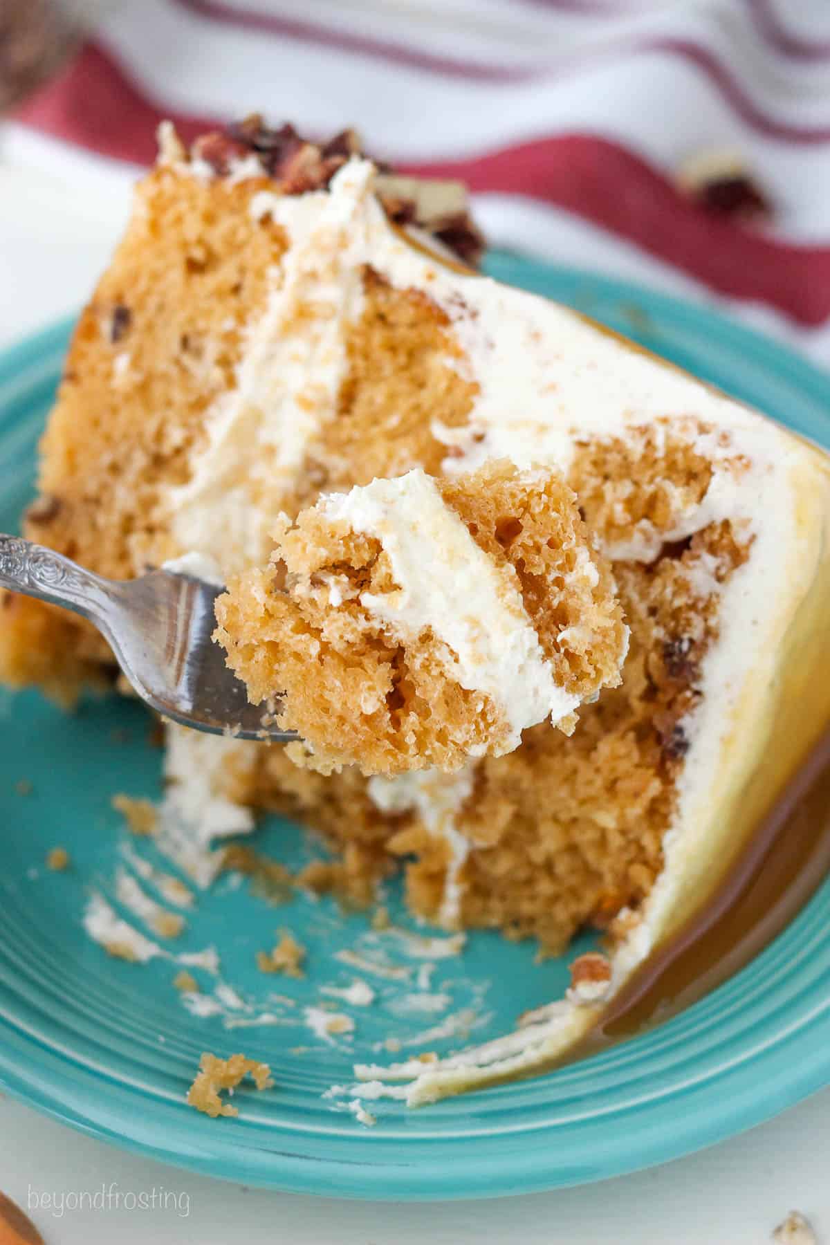 A slice of butterscotch cake on a blue plate with a bite on a fork