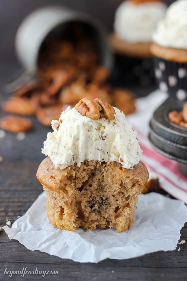 A frosted maple pecan cupcake with a large bite taken out to reveal the light and fluffy interior