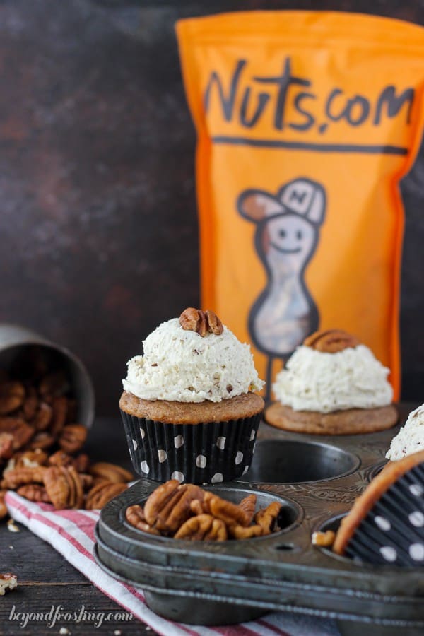 Cupcakes and pecans scattered about a dining room table with a bag of pecans from Nuts.com in the background