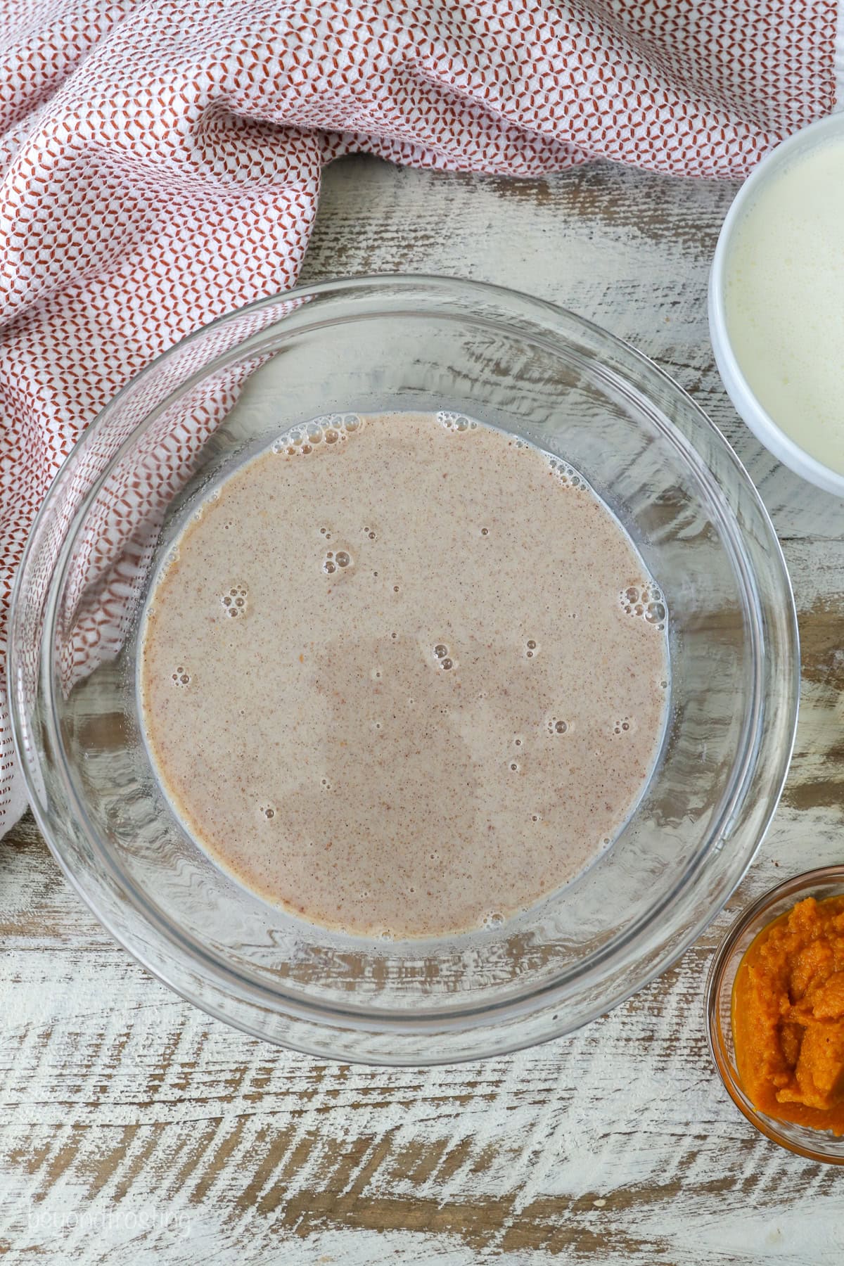 Pumpkin ice cream ingredients combined in a glass bowl.