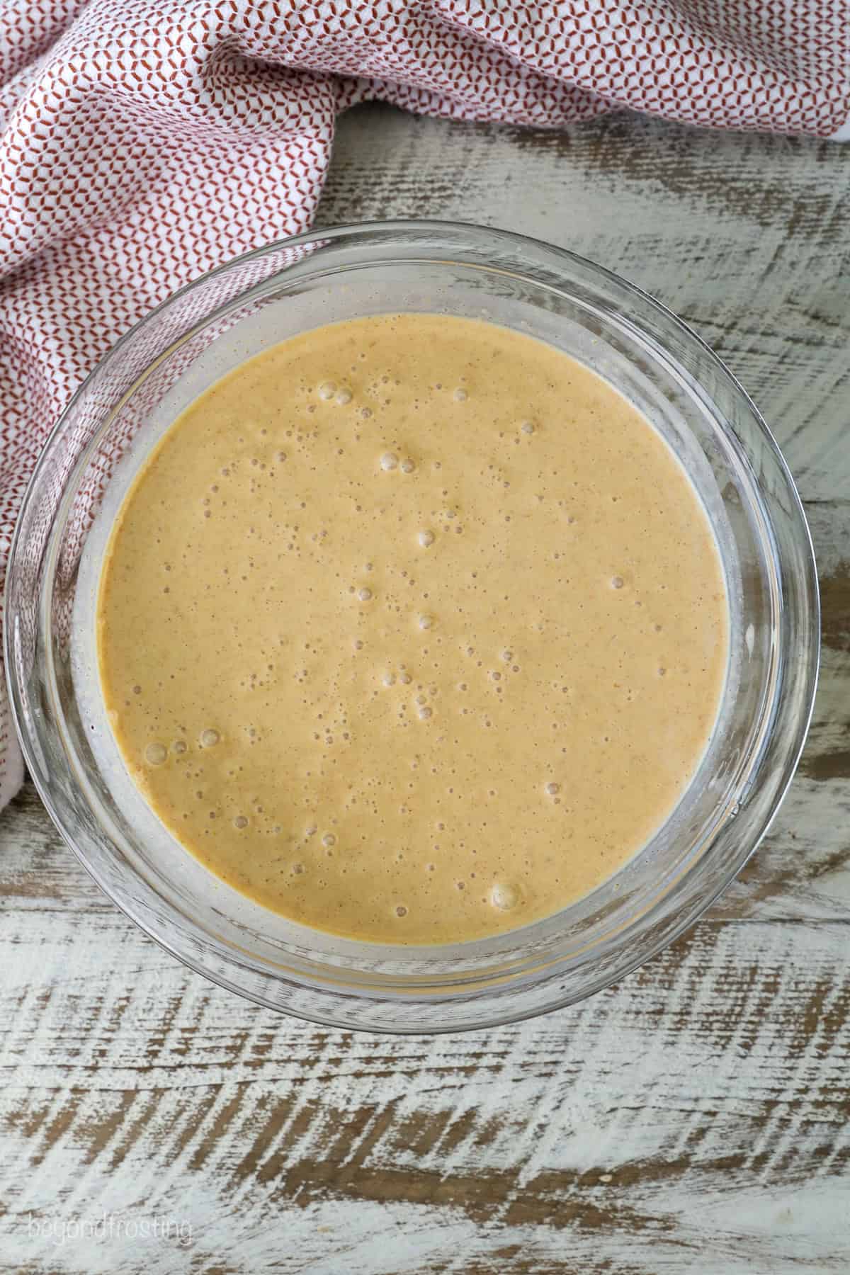 Overhead view of pumpkin pie ice cream mixture in a glass bowl.