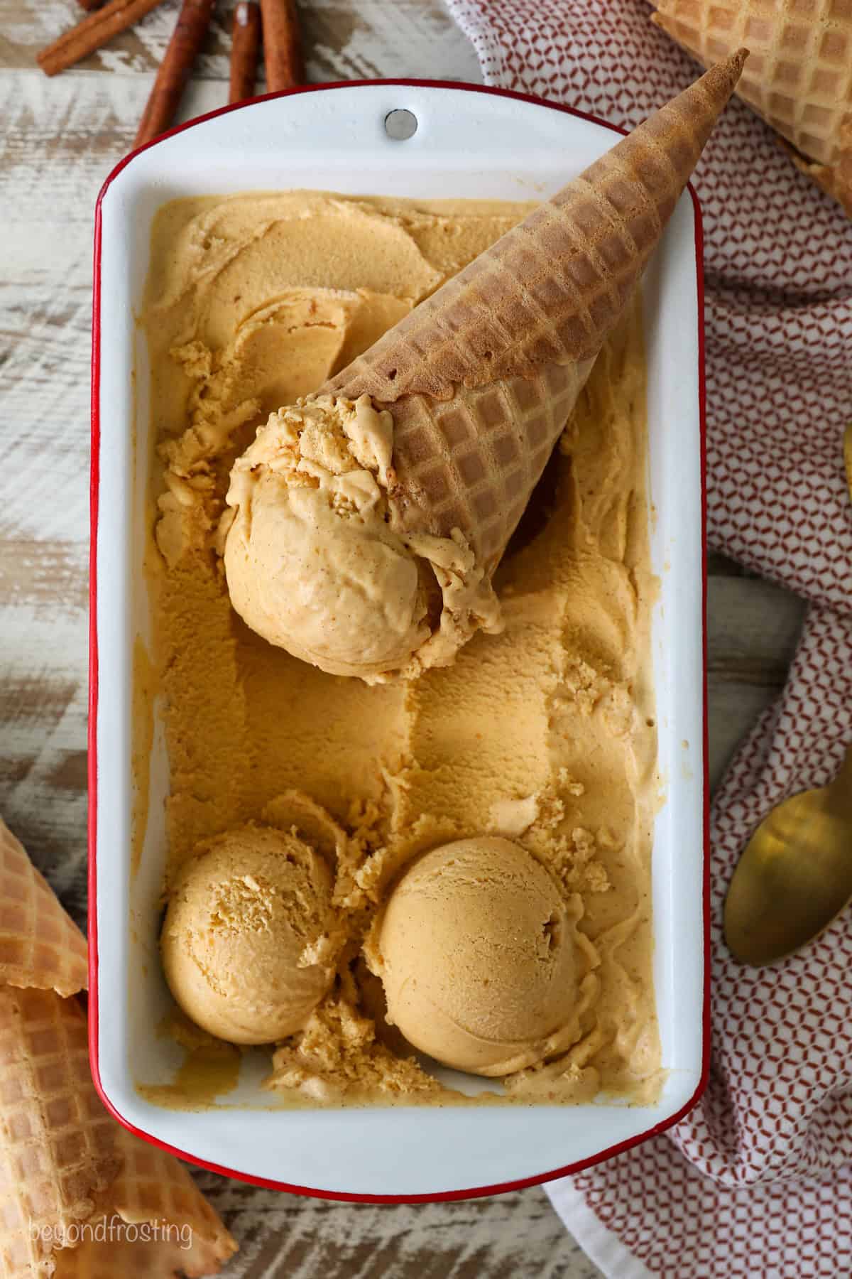 An ice cream cone resting in a loaf pan filled with pumpkin pie ice cream.